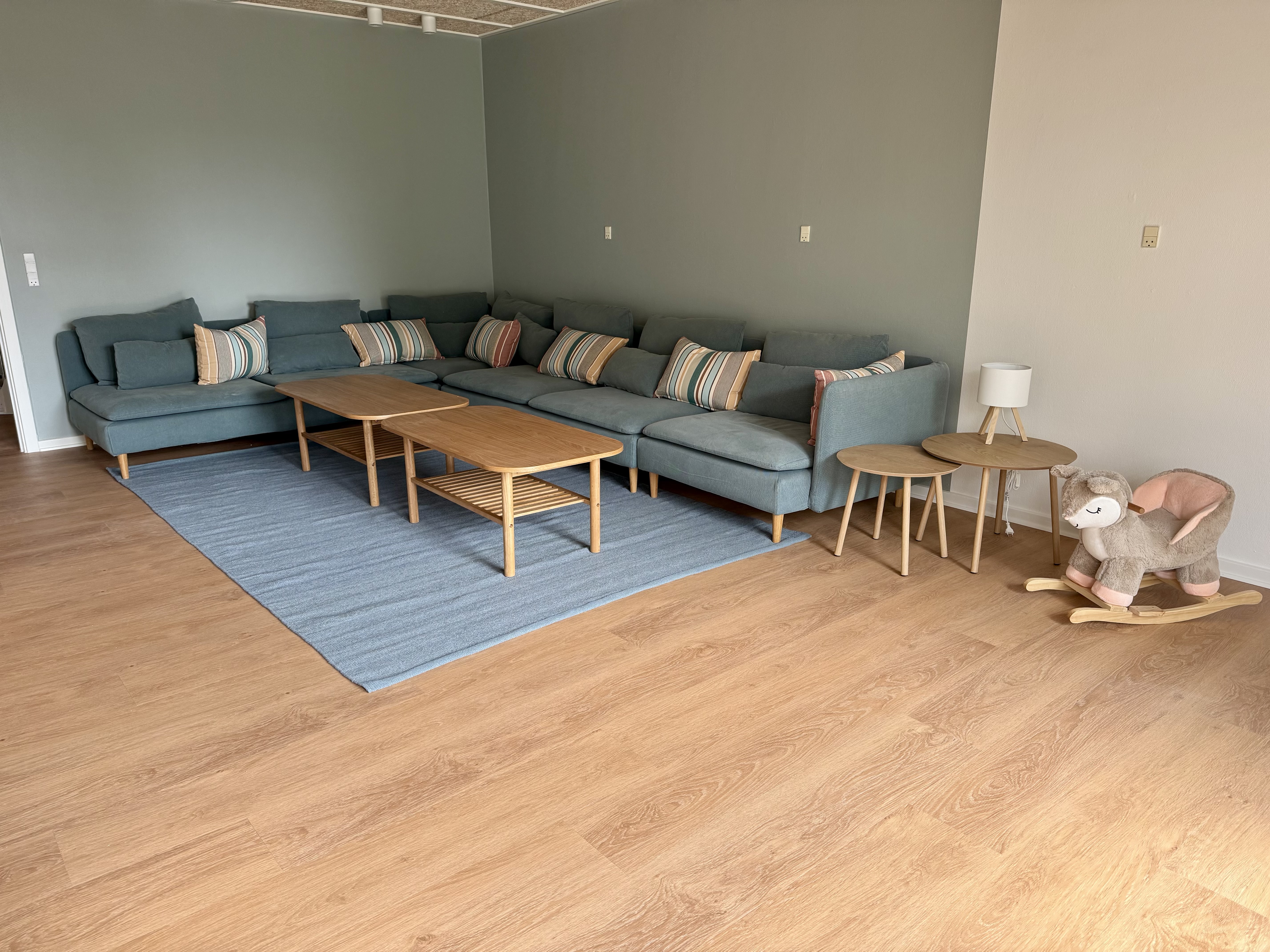 Blå hjørnesofa med puder og gyngehest